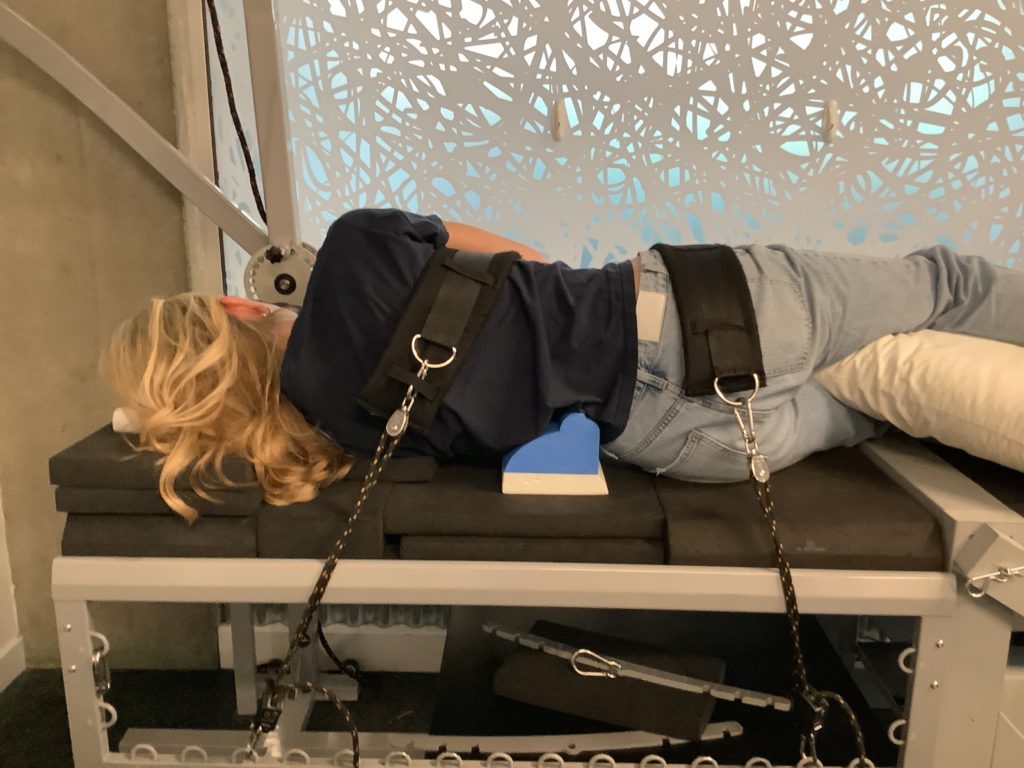 female patient laying on table with back facing receiving 3D Spinal Traction treatment