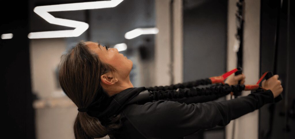 Close-up of a woman performing resistance exercise in a modern clinic, with shallow depth of field and soft background blur.
