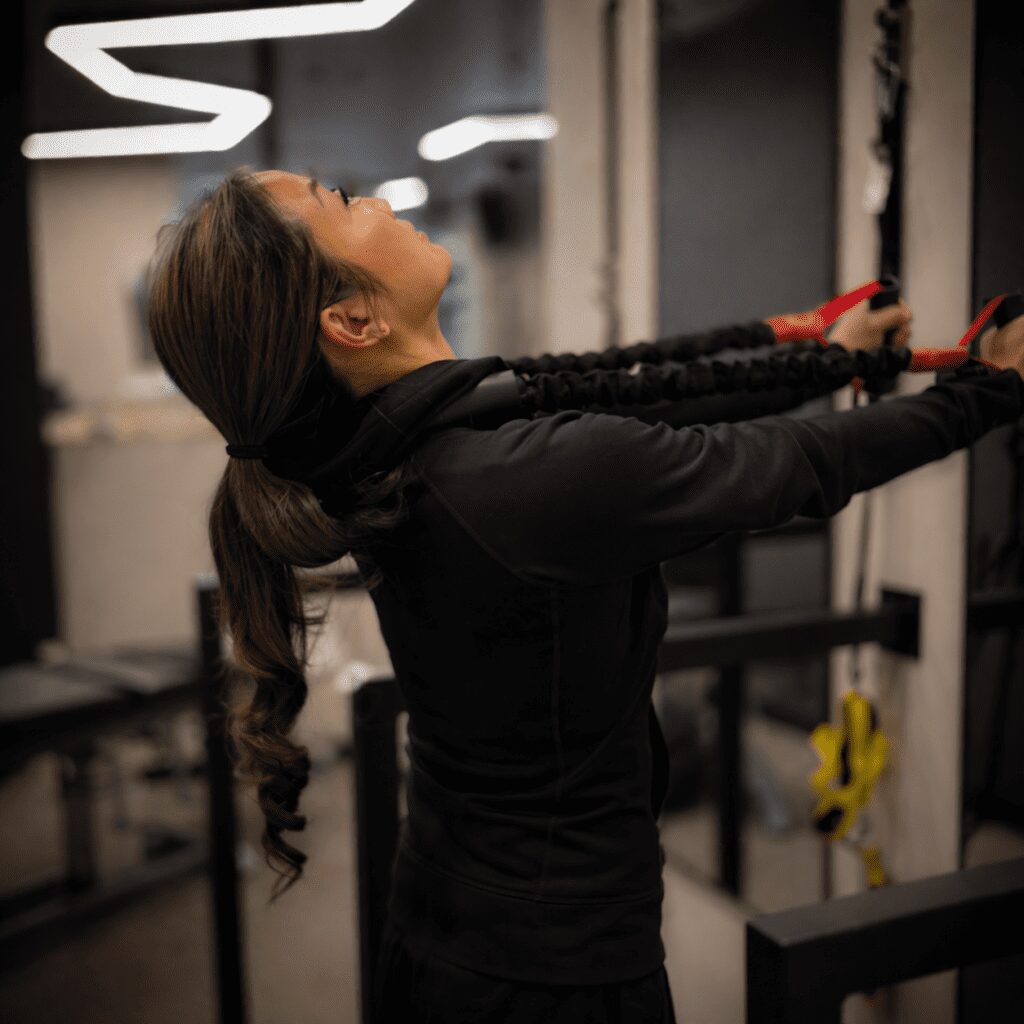 Close-up of a woman performing resistance exercise in a modern clinic, with shallow depth of field and soft background blur.