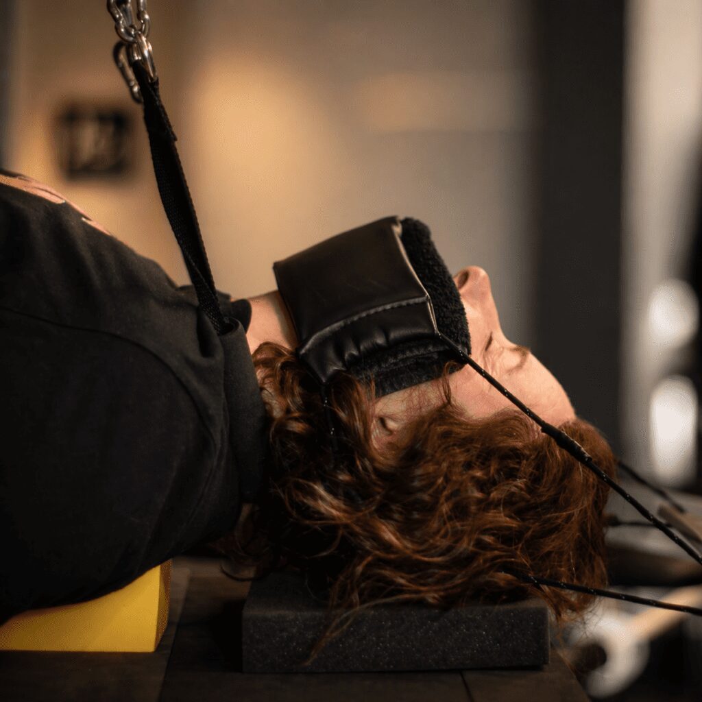 Close-up of a patient receiving neck traction therapy with supportive strap in a softly lit clinical setting.