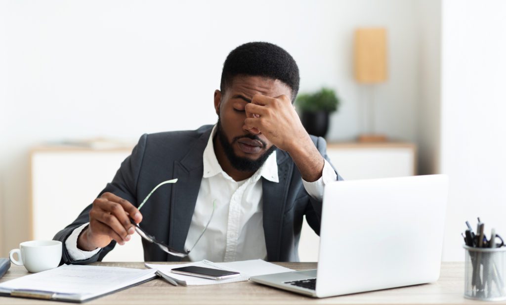 Overworked businessman sitting at workplace after hard day in office